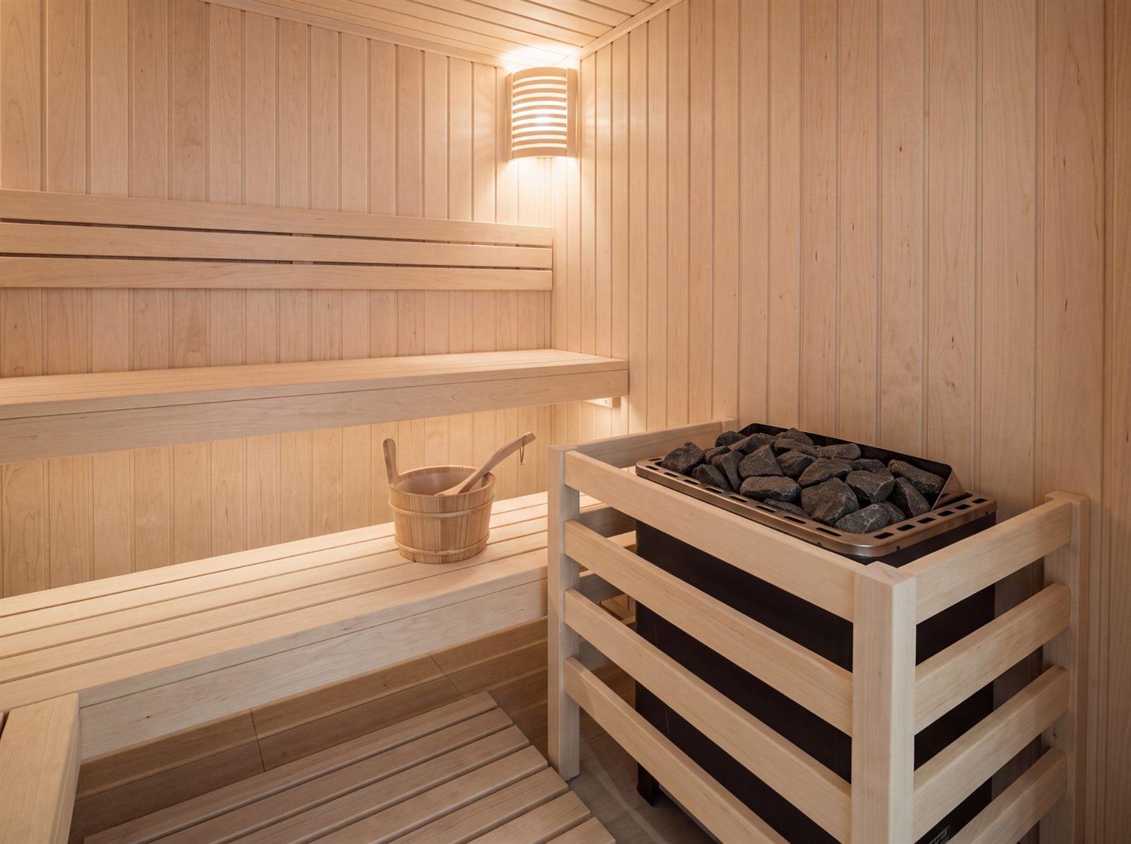 Saunaofen mit Ofenschutz aus Holz in einer hellen Saunakabine aus Espenholz