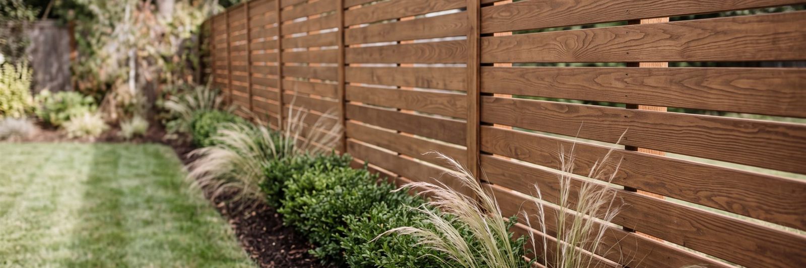 Sichtschutzzaun aus horizontalen Holzbrettern am Gartenrand